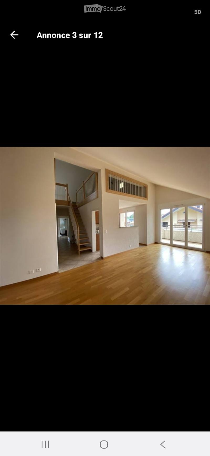Empty room with wooden flooring, white walls, large windows, and a staircase leading to an upper level.