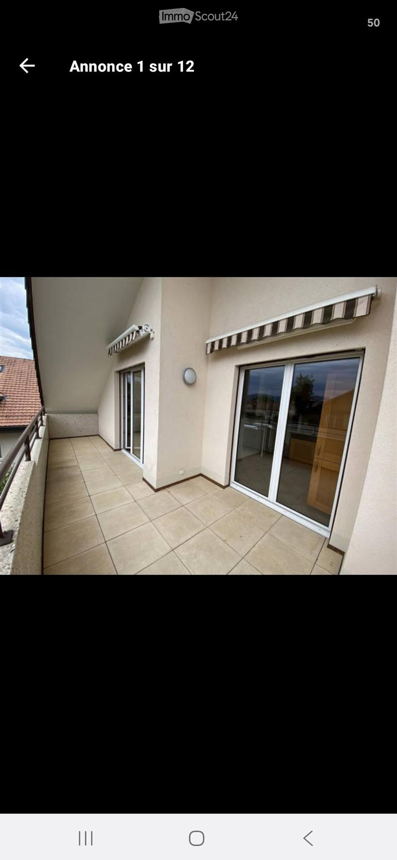Balcony with tiled floor, glass sliding doors, striped awning, and metal railing.