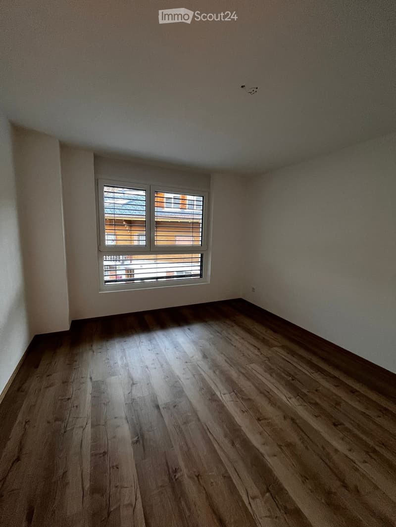 Empty room, wooden floor, white walls, window with white shutters, empty power outlet