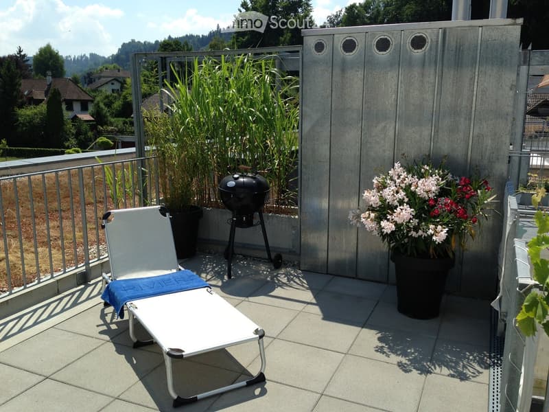 Balcony with tiled floor, lounge chair, barbecue, and potted plants.