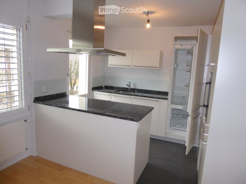 modern kitchen with island, granite countertops, stainless steel appliances, white cabinets, open refrigerator, sink with faucet, exhaust hood, wooden floor