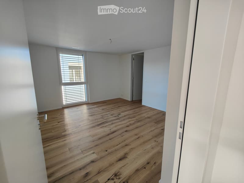 Empty room with light wooden flooring, white walls, and a window with blinds. No furniture or equipment present.