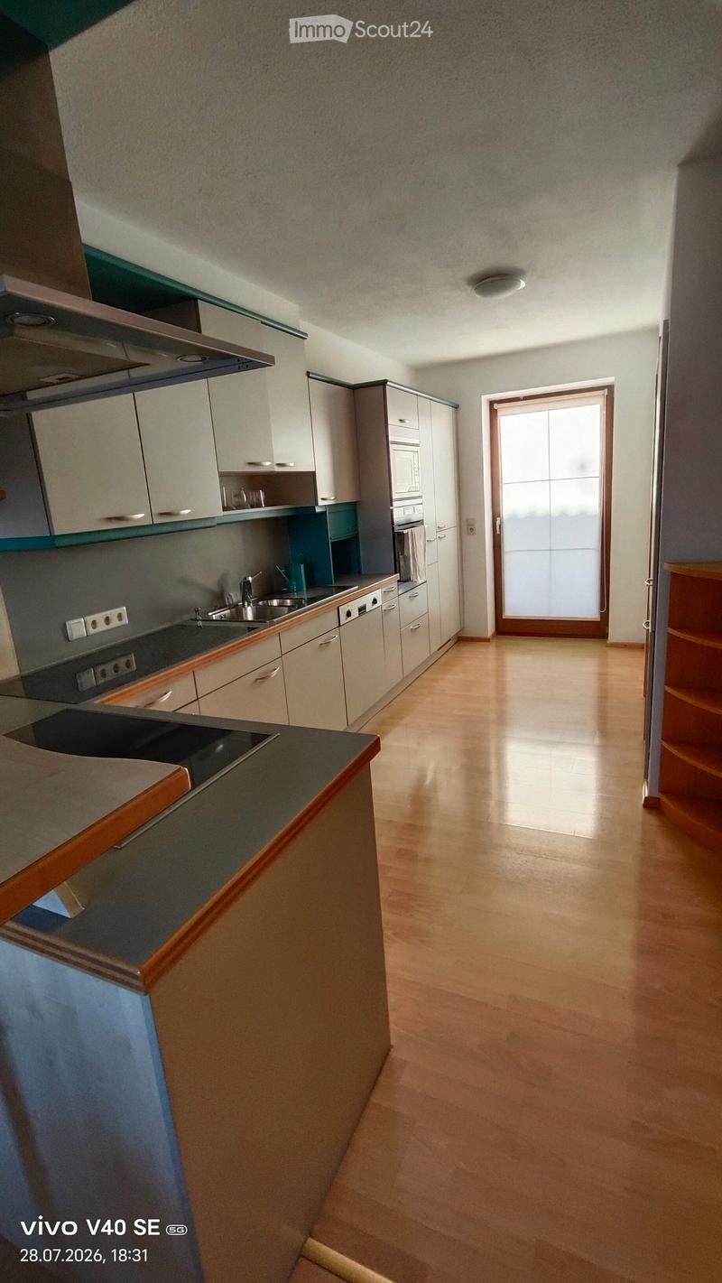 Modern kitchen with light-colored cabinets, stainless steel appliances, and a central island with a dark countertop.