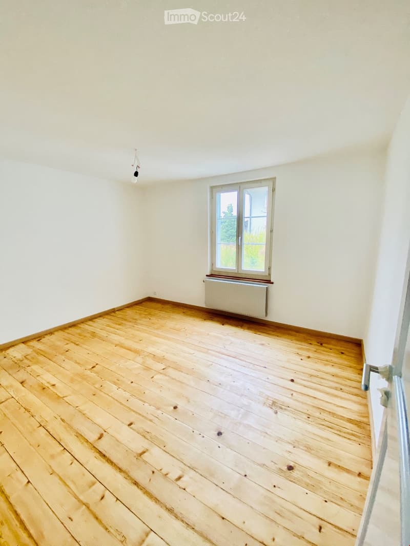 Empty room with wooden flooring, white walls, and a single window with a radiator below it. No furniture or equipment is present.