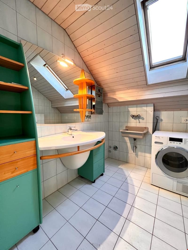 white tiled walls, white sink, mirror, green cabinets, washing machine, small sink, wooden ceiling