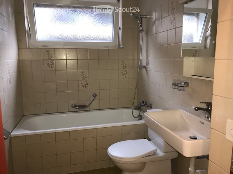 Bathroom with a bathtub, toilet, sink, shower, and a small window for natural light.