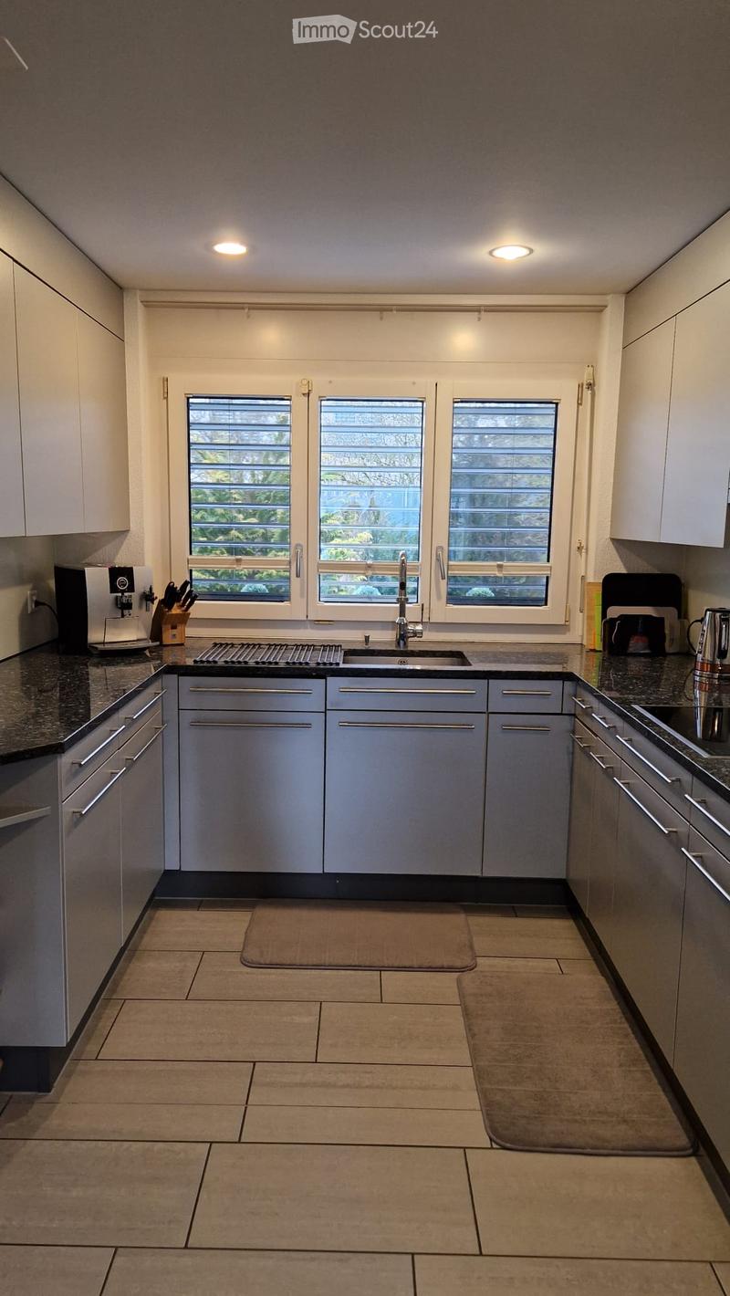 Modern kitchen with white cabinets, stainless steel appliances, granite countertops, and a tiled floor. Features a sink with a modern faucet, a coffee maker, and a knife block on the counter.