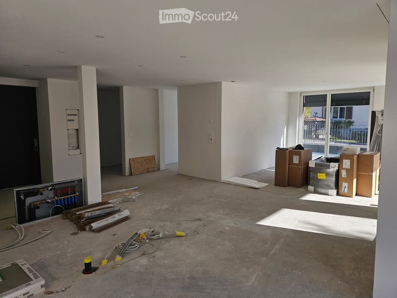 Empty room with bare walls, concrete floor, and scattered construction materials and boxes. No furniture or appliances present.