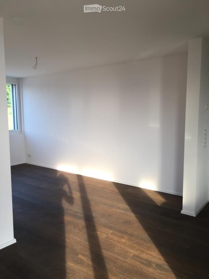 Completely empty room with bare white walls and dark wooden flooring. No furniture or equipment present.