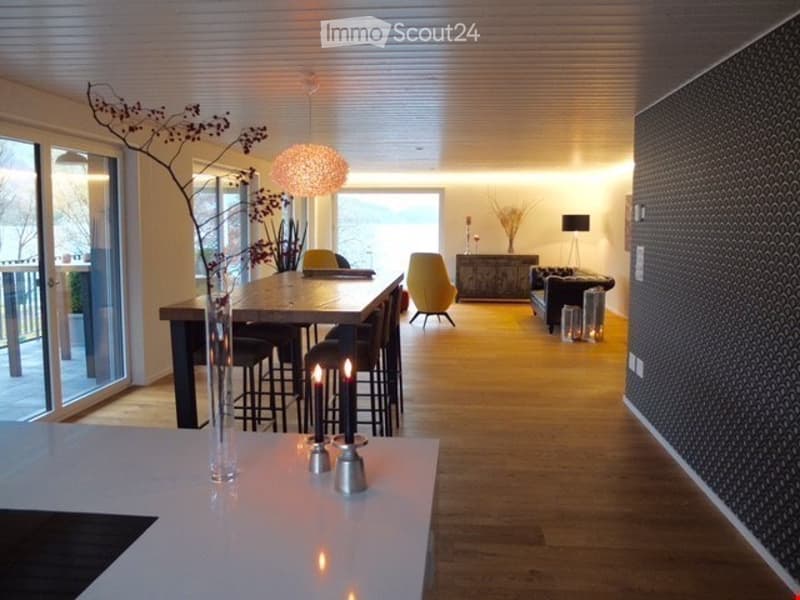 Open-plan living and dining area with modern furniture, large windows offering a view, and warm lighting.