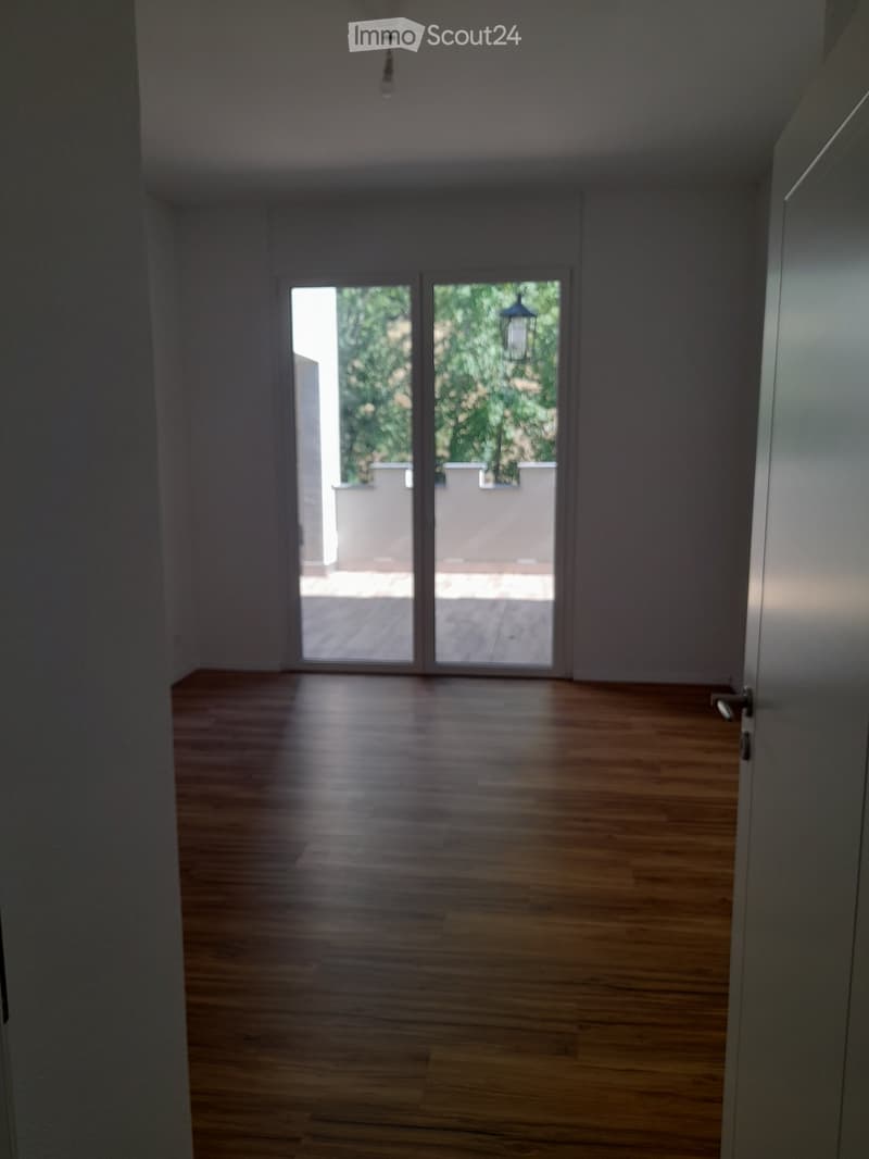 Empty room with wooden flooring and large sliding glass doors leading to an outdoor area.