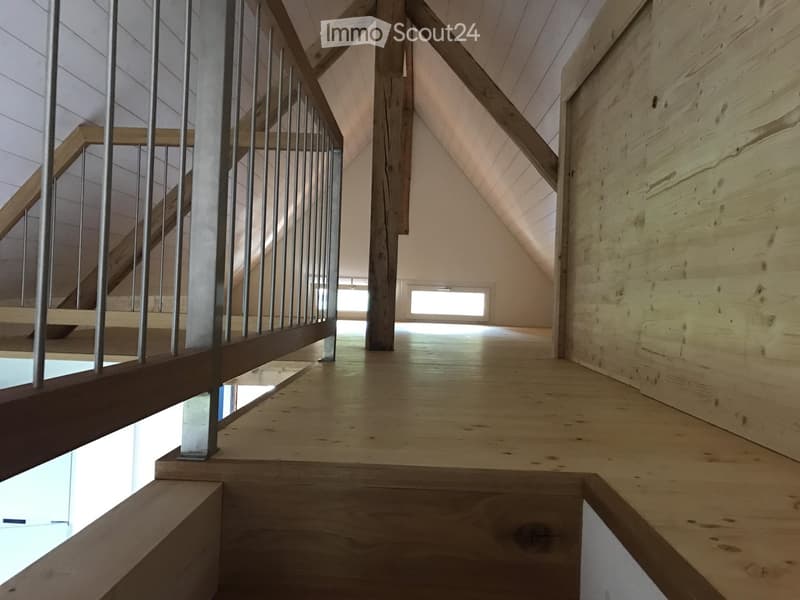Wooden staircase with metal railing, wooden walls, and a skylight window at the end of the hallway.