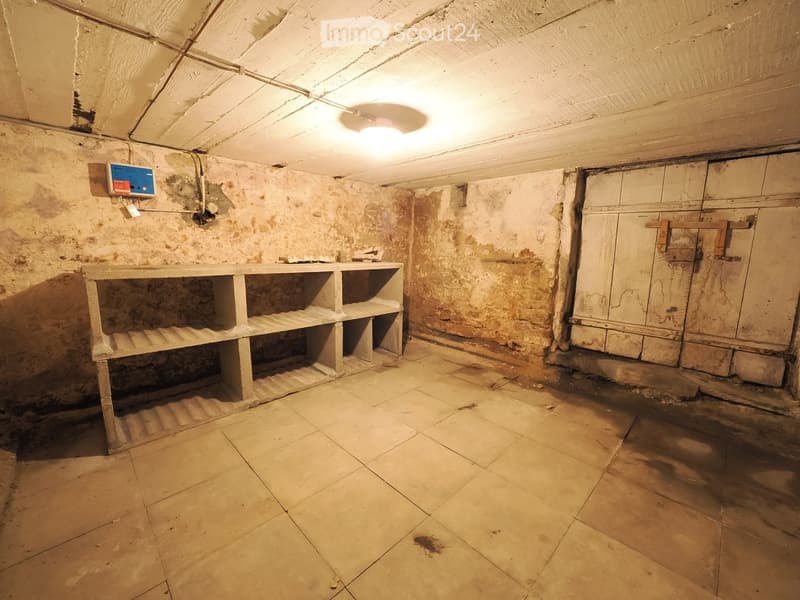 Empty room with exposed brick walls, tiled floor, and a single shelf unit. No furniture or equipment present.