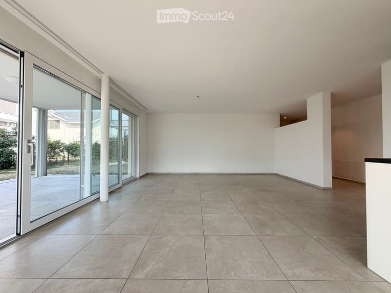 Empty room with large sliding glass doors leading to an outdoor area, tiled floor, white walls, and a white column.