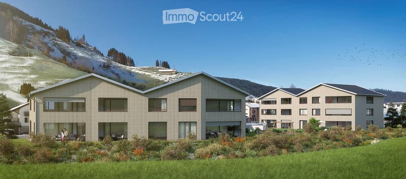 Modern two-story residential building with large windows and balconies, surrounded by a well-maintained garden and a snow-covered mountain backdrop.