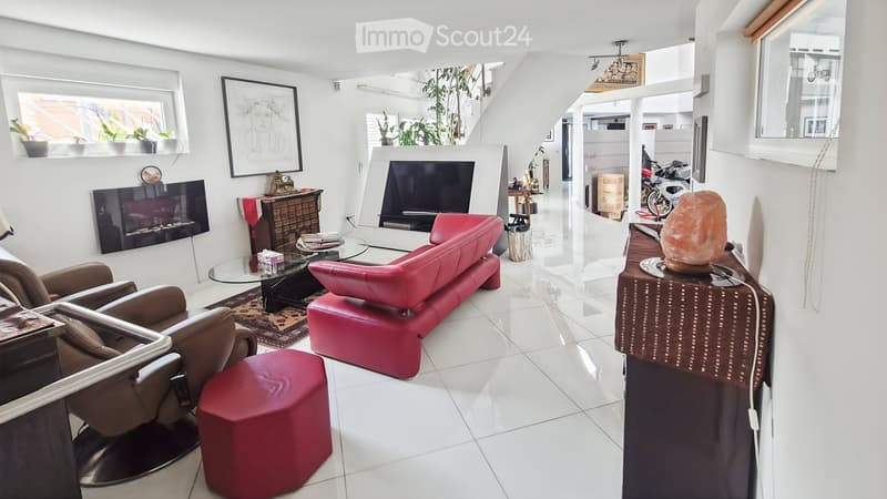 Modern living room with white tiled flooring, red leather sofa, glass coffee table, fireplace, and decorative items.