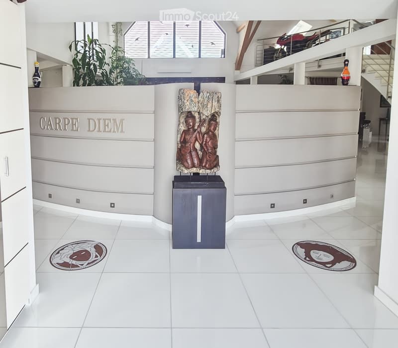 Modern hallway with white tiled floors, white walls, decorative artwork, and a staircase leading to an upper level.