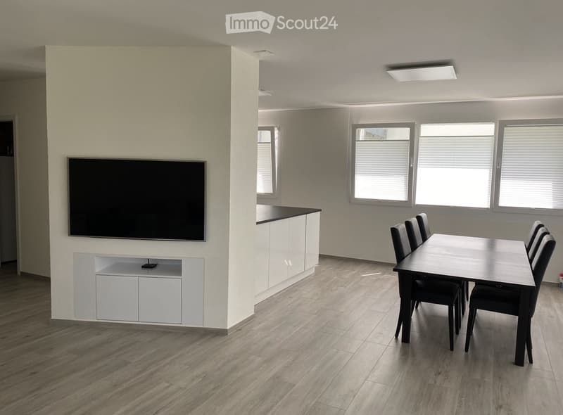 Living room: wooden floor, flat screen TV, dining table, 4 chairs, kitchen, large windows with blinds, recessed ceiling lighting