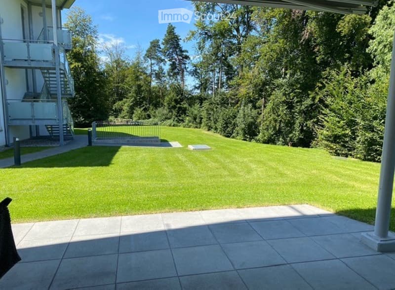 lawn with trees and shrubs, stairs leading to building, paved walkway, garden with bench