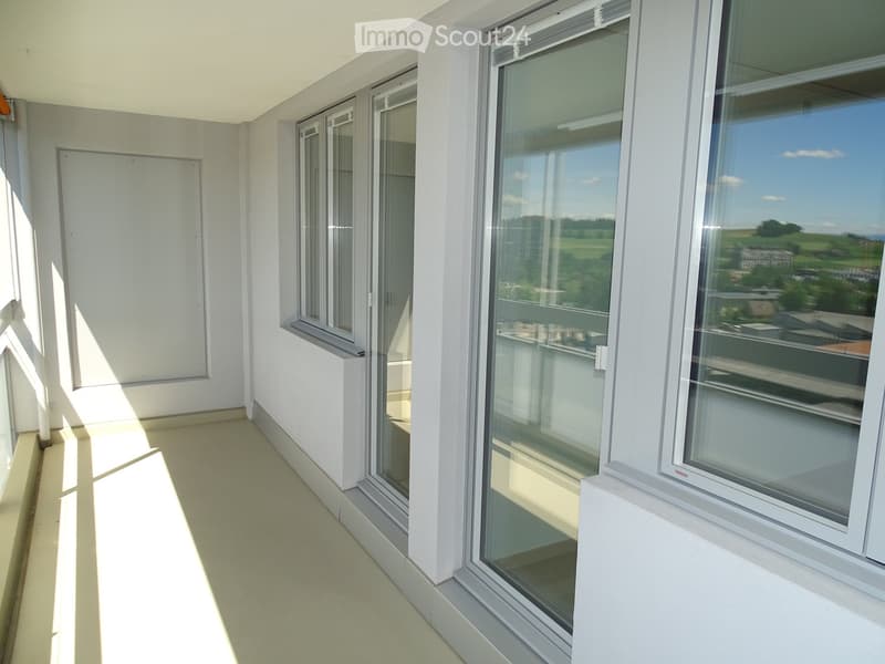 Terrace, with glass sliding doors, white walls, wooden floor, doors to rooms.