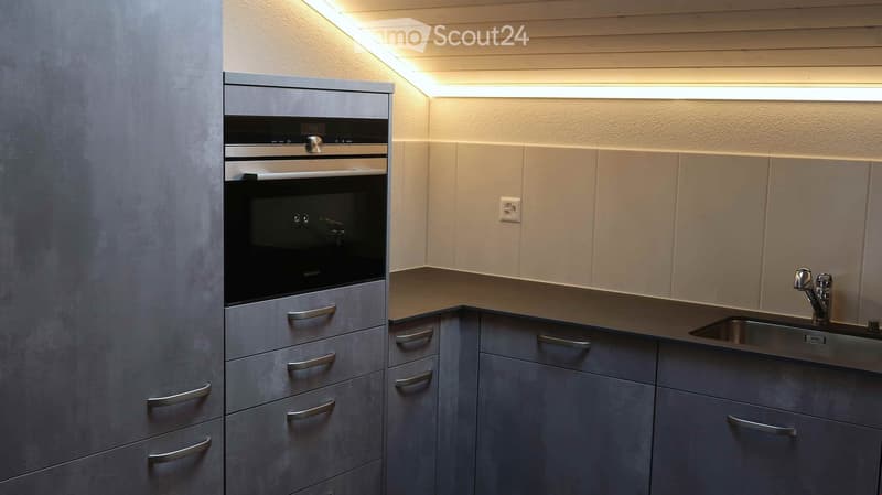 Modern kitchen with grey cabinets, stainless steel oven, and sink with faucet.