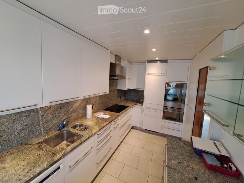 Modern kitchen with white cabinets, granite countertops, stainless steel sink, and built-in oven.