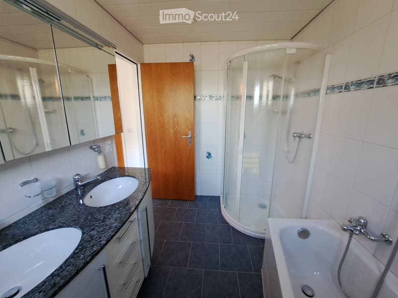 Modern bathroom with a double sink vanity, bathtub, glass-enclosed shower, and mirrored cabinet.