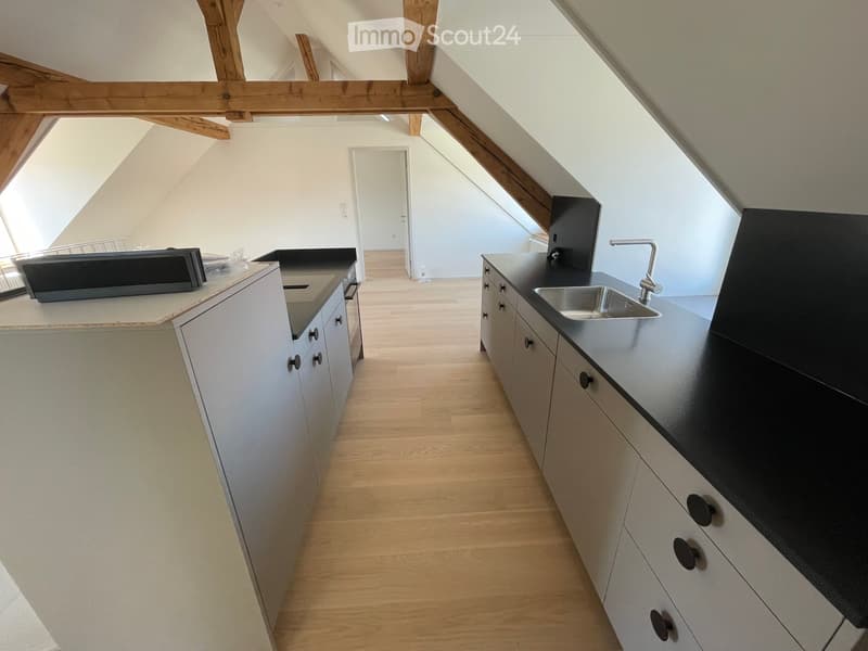 Kitchen. Modern kitchen with white cabinets, black countertops, and a stainless steel sink. Wooden flooring and exposed wooden beams on the ceiling.