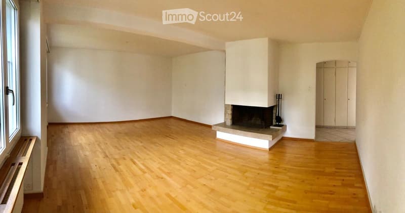 Empty room with wooden flooring, white walls, and a built-in fireplace with a white surround.