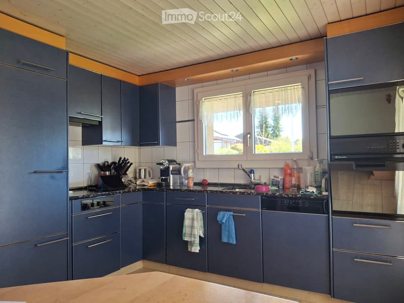 Modern kitchen with dark blue cabinets, stainless steel appliances, and a wooden countertop. Features include a refrigerator, oven, microwave, sink, and various kitchen utensils.