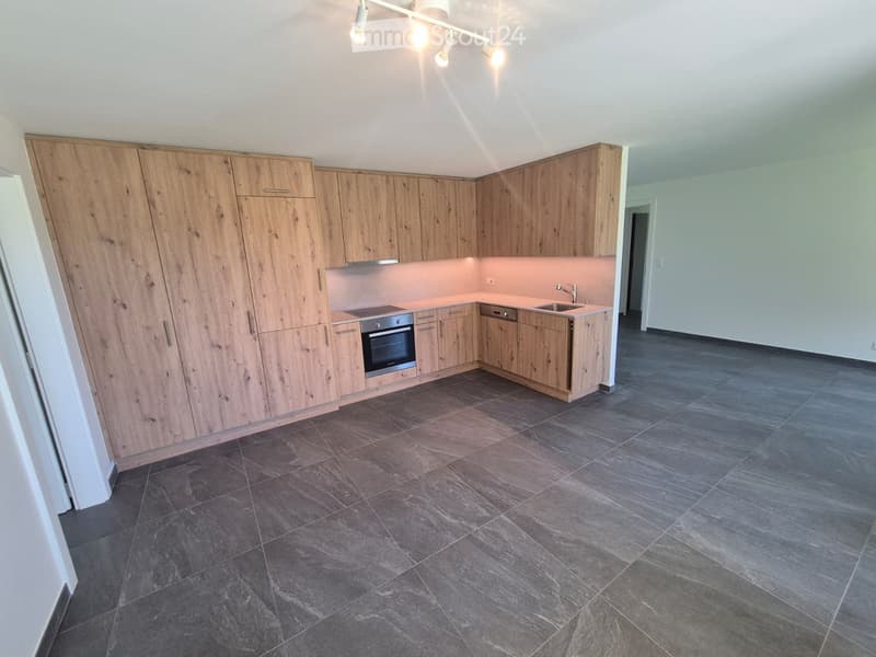 Modern kitchen with light wood cabinetry, stainless steel oven, sink, and faucet, featuring dark tiled flooring and recessed lighting.