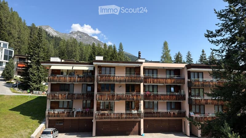 Multi-story building with balconies, garage, and scenic mountain view.