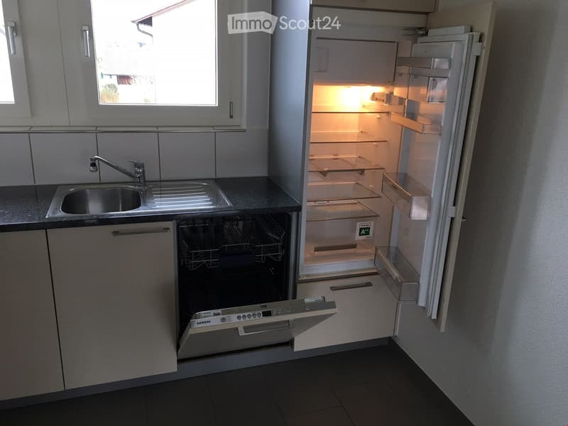 Open refrigerator, dishwasher, stainless steel sink, silver faucet, tile flooring, cabinets
