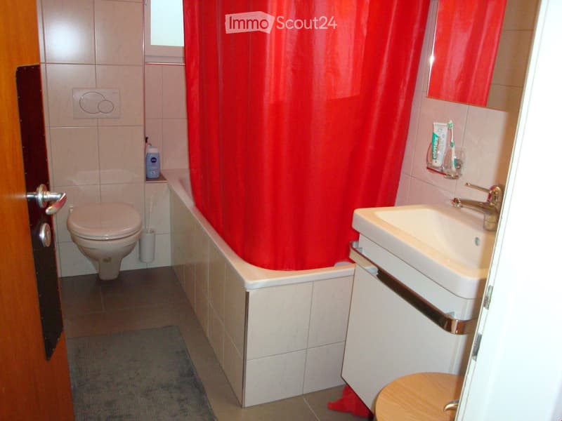 Bathroom with bathtub, shower curtain, sink, mirror, toilet, and wooden stool.