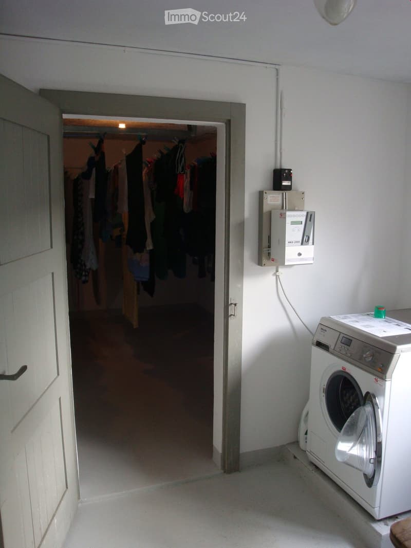 washer in the corner, wall mounted box, door leading to another room
