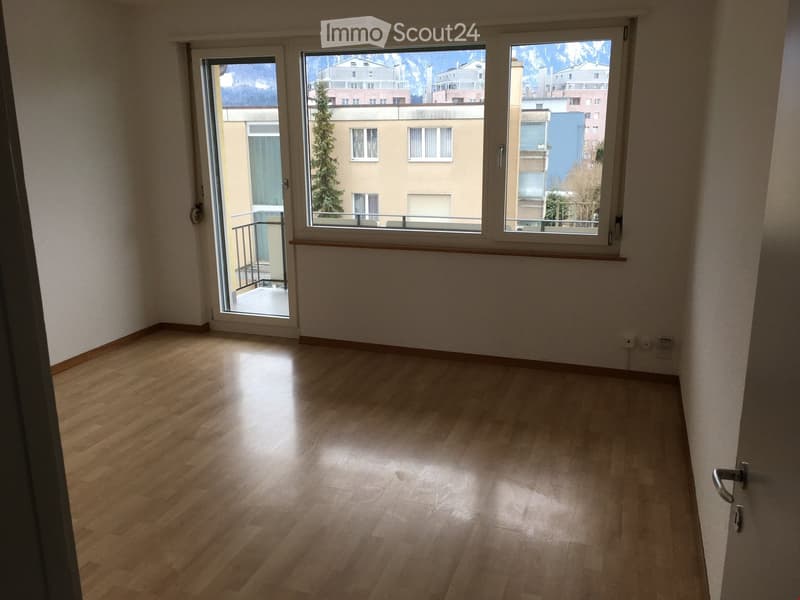 Empty room, hardwood floors, sliding glass door leading to balcony, large windows, power outlets on wall