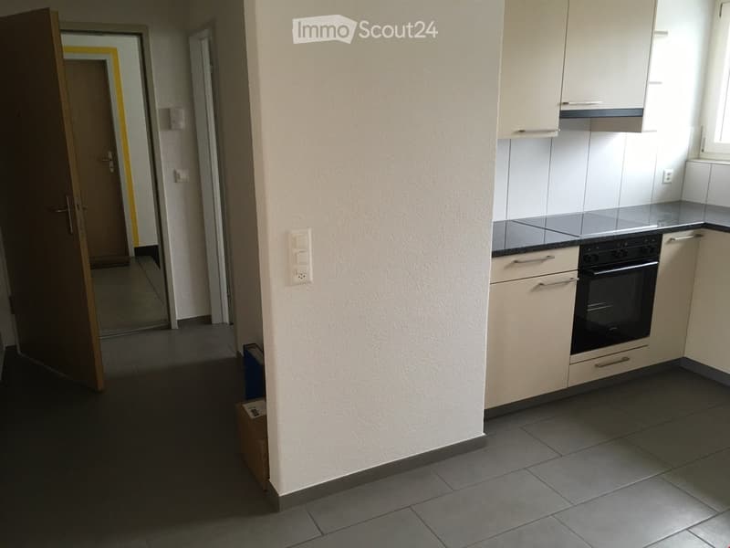 Open door to kitchen, modern white kitchen, tiled floor, cabinet under oven, switch, gas stove top