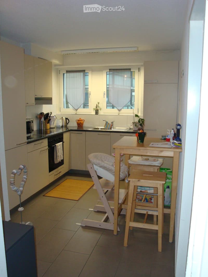 kitchen with appliances and wooden table, stools, microwave, refrigerator, sink, and windows with curtains