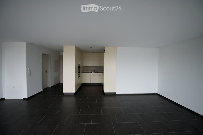 Modern kitchen with white cabinets, black tiled floor, and stainless steel appliances including a sink and oven.
