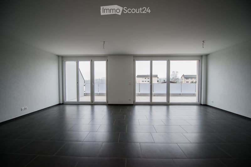 Empty room with dark tiled floor, white walls, and large sliding glass doors leading to a balcony.