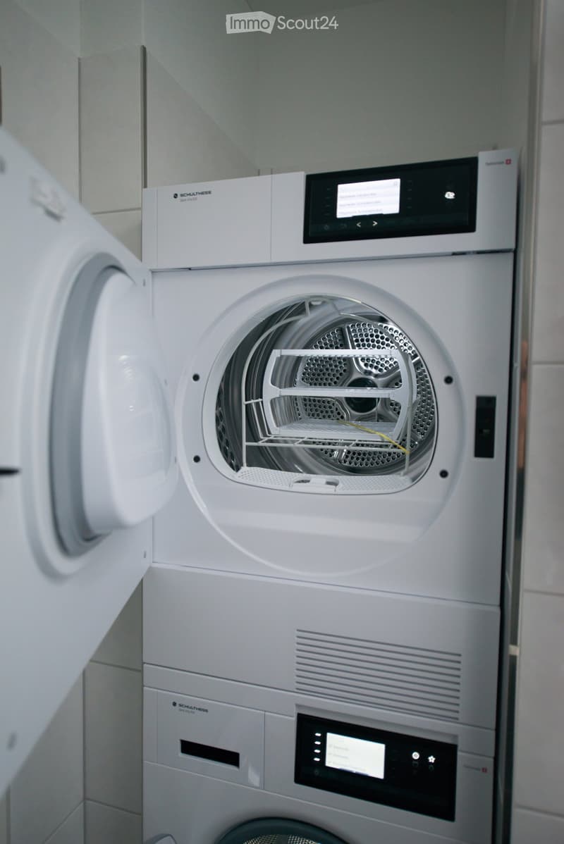 Modern bathroom with a white washing machine and dishwasher, both featuring digital control panels.
