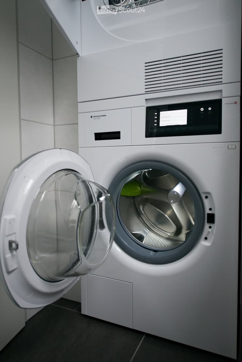 Modern bathroom with a white washing machine and dishwasher, both with open doors showing their interiors.