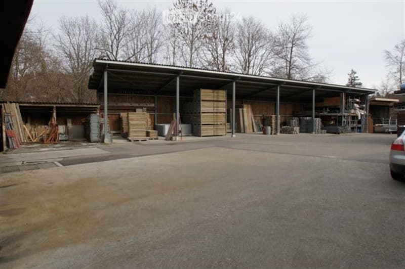 Large industrial-style building with a metal roof and open sides, used for storage of construction materials and equipment.