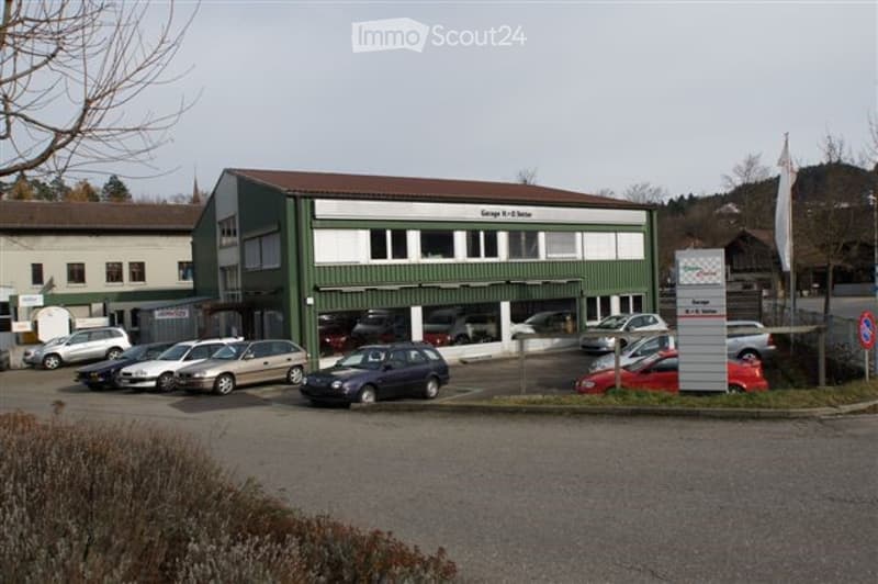 Modern industrial-style building with green and white facade, multiple windows, and a sign reading "Georg K. H. Meyer". Several cars are parked in front of the building.