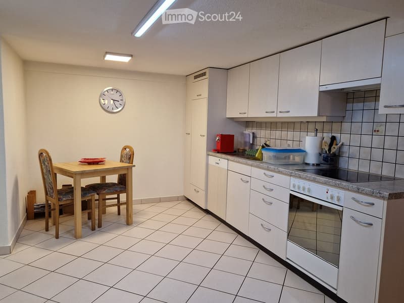 Modern kitchen with white cabinets, tiled floor, and a small dining area with a table and chairs.