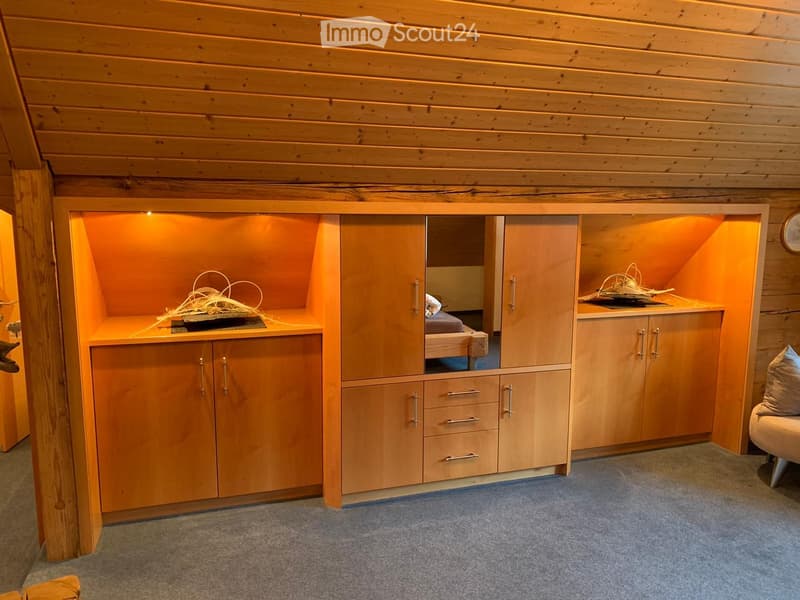 A cozy, wooden-paneled room with built-in cabinets, a small bed, a sofa, and a table with decorative items.