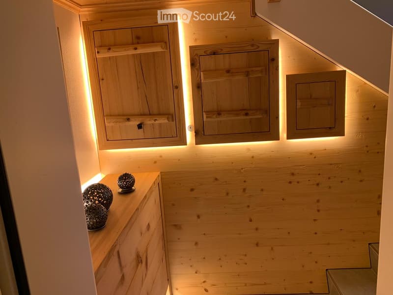 Wooden hallway with built-in storage compartments and decorative spheres on a drawer unit.