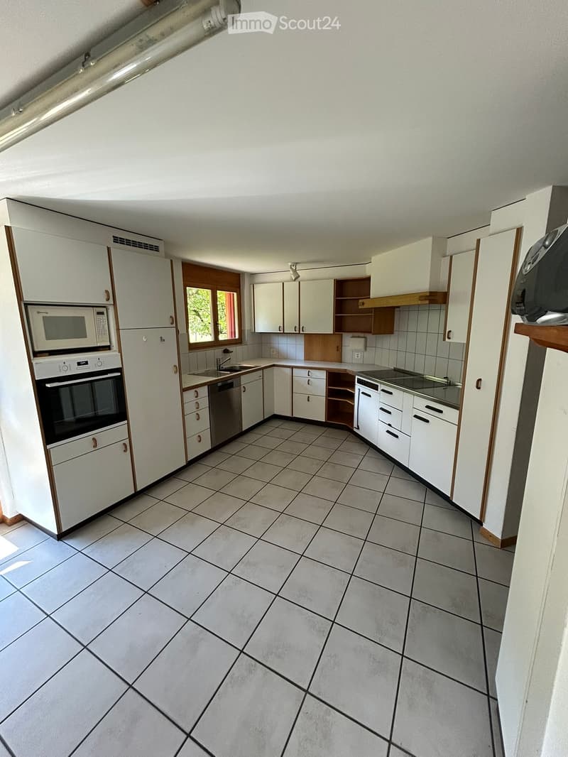 Modern kitchen with white cabinets, tiled floor, microwave, oven, dishwasher, and sink.
