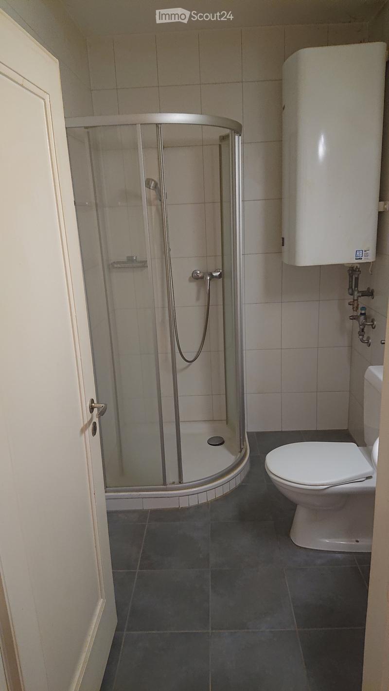 Modern bathroom with a glass-enclosed shower, toilet, and tiled walls and floor.