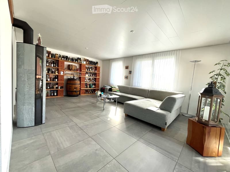 Modern living room with grey sectional sofa, coffee table, wine rack, barrel, floor lamp, and decorative lantern on a wooden stand.